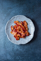 Overhead view of fresh cooked bacon in a blue plate with copy space