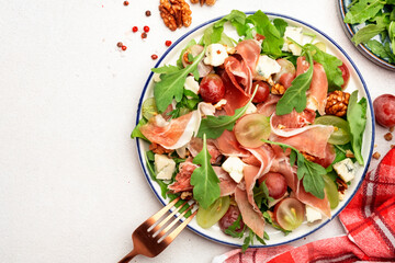 Freash grape salad with jamon, blue cheese, arugula, nuts on white table background, top view, copy space