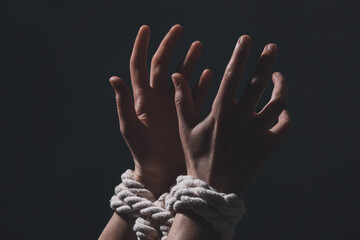 Tied together hands of hostage on dark background