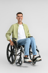 Young man in wheelchair on light background