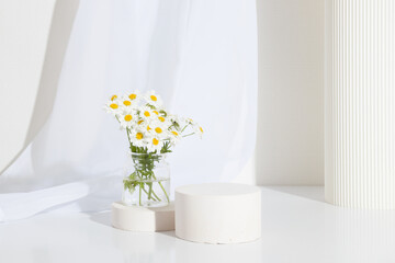 Empty cylindrical podium or plinth with chamomile flowers on white background. Empty shelf product standing background