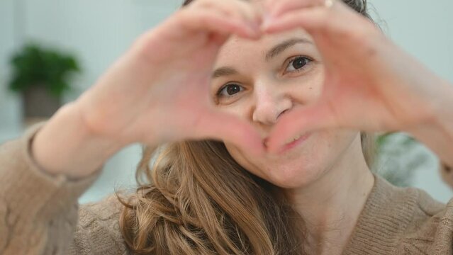 Smiling woman shows heart shape with her fingers