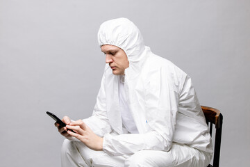 Tired doctor wearing mask and gloves at the hospital in coronavirus times, checking his smartphone.