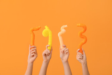 Hands with popular pop tubes on color background