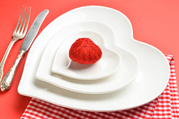 Fototapeta na wymiar Beautiful heart-shaped plates and cutlery on red background, closeup