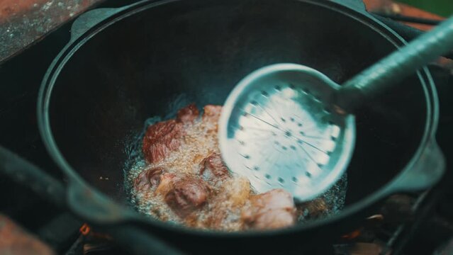 Meat is cooked in cauldron on fire. Step by step cooking of Pilaf.
