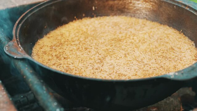 Rice is cooked in cauldron on fire. Step by step cooking of Pilaf.