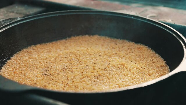 Rice is cooked in cauldron on fire. Step by step cooking of Pilaf.