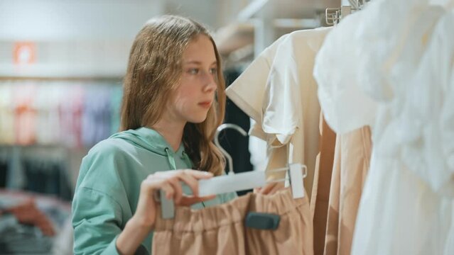 Teenage girl choosing clothes in mall.