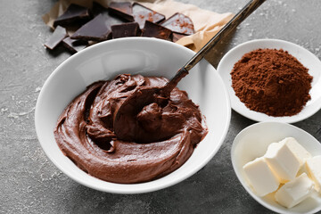 Bowl with fresh dough and ingredients for preparing chocolate brownie on grey background