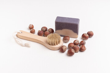 Fototapeta na wymiar Wooden brush for facial or body massage, soap and hazelnuts. Nut scrub. Natural skin care kit