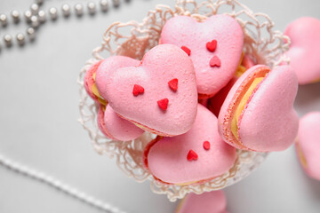 Bowl with tasty heart-shaped macaroons on grey background, closeup
