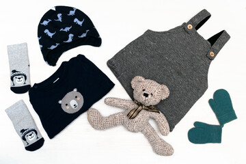 Knitted romper, sweater, jumper, hat, socks, mittens, teddy bear. Set of Fashion newborn baby childs clothes and accessories in pastel colors on white background. Flat lay, top view