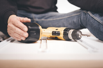 Man unpacking and assembling set of three drawers