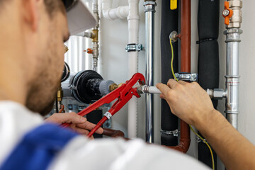 plumber working with pipelines. tighten plumbing fittings