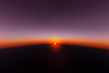 A magical view of the sun setting down at dusk from the window of an airplane