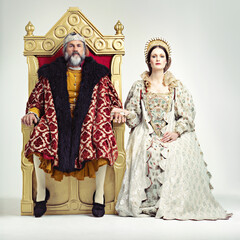 They rule sternly but fairly. Studio shot of a king and queen sitting on thrones. - obrazy, fototapety, plakaty