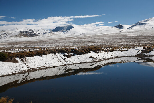 Landscape of the puna of Peru, snowy, with a lagoon and ichu plants