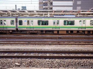 Train convoy stopping at station and railroad seen from the platform of Hachioji station