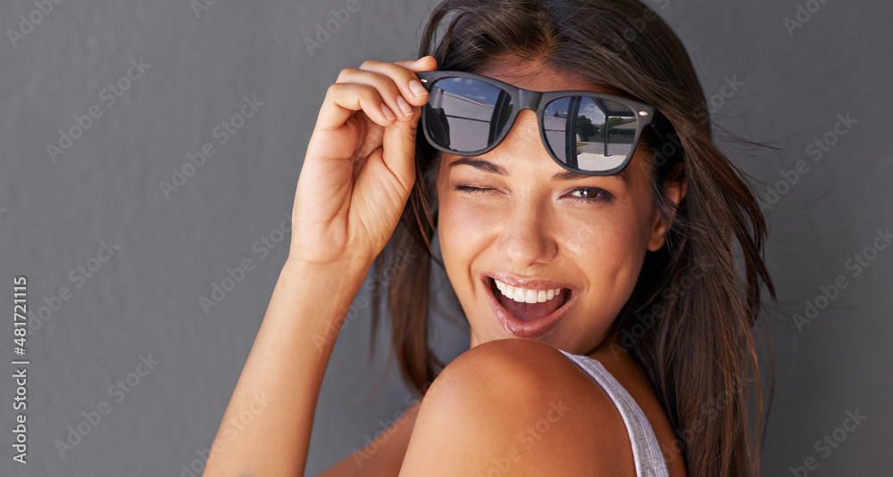 Poster Hey you.... Shot of an attractive young woman winking at the camera while holding up her sunglasses.