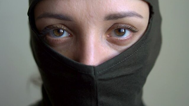 Female portrait of young girl wearing khaki balaclava, only eyes are visible, mandatory conscription, military, feminism, equality concept