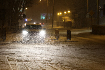 Pojazdy pług i piaskarka na drodze po nocnych opadach śniegu w mieście i ruch pojazdów. 