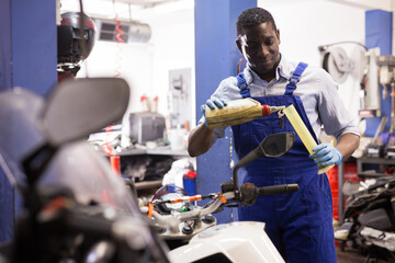 Engineer in overalls pours oil for motorcycle engine in garage. High quality photo
