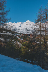 A picturesque vertical shot of the snowcapped French Alps mountains and the ski resort buildings on a cold winter day (La Joue du Loup, Devoluy)