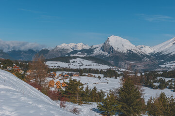 A picturesque landscape view of the snowcapped French Alps mountains and the ski resort buildings...
