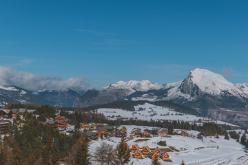 A picturesque landscape view of the snowcapped French Alps mountains and the ski resort buildings on a cold winter day (La Joue du Loup, Devoluy) - obrazy, fototapety, plakaty