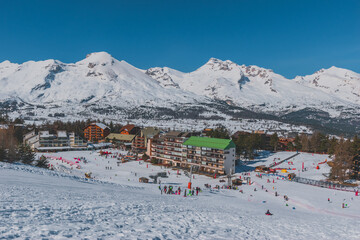 A picturesque landscape view of the snowcapped French Alps mountains and the ski resort buildings on a cold winter day (La Joue du Loup, Devoluy) - obrazy, fototapety, plakaty