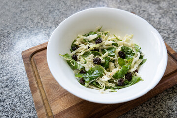 Top view of fresh salad with greens, raisins and cheese