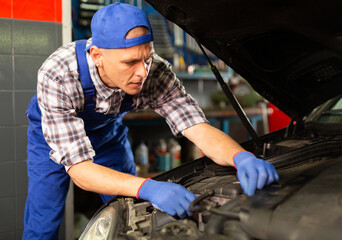 Positive man car mechanician repairing car in auto repair shop