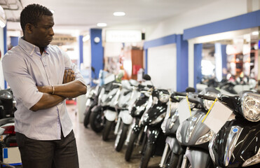 Fototapeta na wymiar Portrait of adult man buying new motorcycle at modern showroom. High quality photo