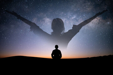 Silhouette of young female sitting practices yoga and meditating in lotus position alone on top of the mountain with night sky, star, Milky Way. She felt calm and happy..