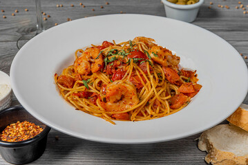 Spicy spaghetti with shrimps and seafood in tomato sauce