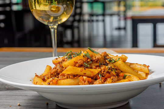 Italian food and pasta pene with bolognese sauce and wine on plate