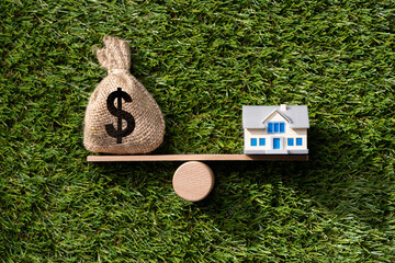 Closeup Of Model Home And Money Balancing