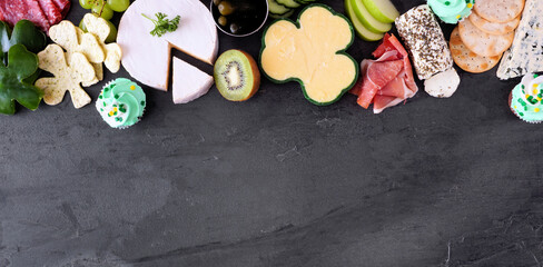 St Patricks Day theme charcuterie top border against a slate background. Selection of cheese, meat,...
