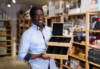 Male shopper chooses wooden box in furniture shop