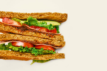 Closeup of healthy sandwich with whole grain bread, vegan ham, tomato, lettuce and avocado.
