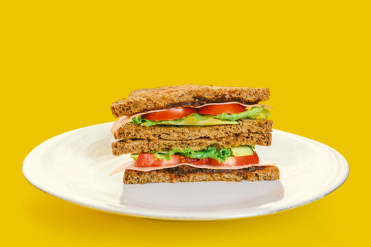 Front view of healthy sandwich with whole grain bread, vegan ham, tomato, lettuce and avocado.