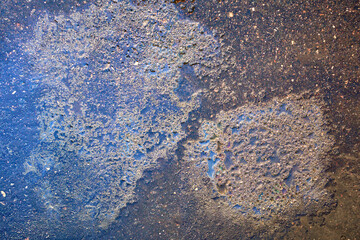 Colorful gas stain on wet asphalt. Oil stain caused by a leak under a car or truck.
