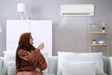 Young Woman Operating Air Conditioner