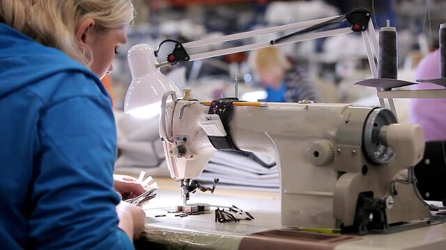 A woman works in a garment factory. A woman works on a sewing machine. Making textiles in a factory