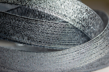 Defocused full frame macro abstract texture background view of shimmering metallic silver fabric ribbon
