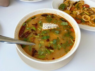 Spicy fish soup flavored with lemongrass and lime served on table