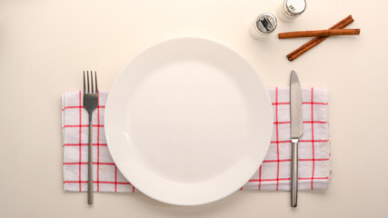 Empty white ceramic plate mockup with cutlery.