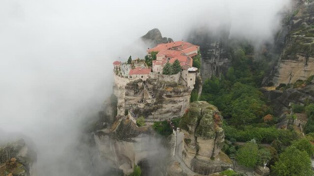 Meteora, Greece, UNESCO World Heritage Site. Aerial View of Orthodox Monastery on Top of Cliff in Dense Morning Fog, Drone Shot