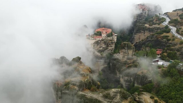 Meteora, Greece. Cinematic Aerial View of Orthodox Monasteries on Top of Cliffs Under Dramatic Fog - Drone Shot